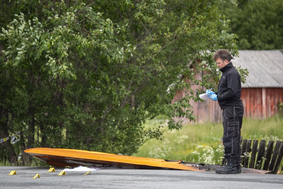 Ein Polizist steht neben den Wrackteilen eines Kleinflugzeugs.