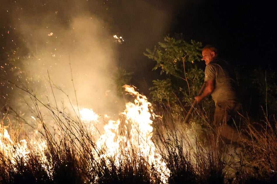 Ein Mann versucht, die Flammen eines Feuers im italienischen Mirto einzudämmen.