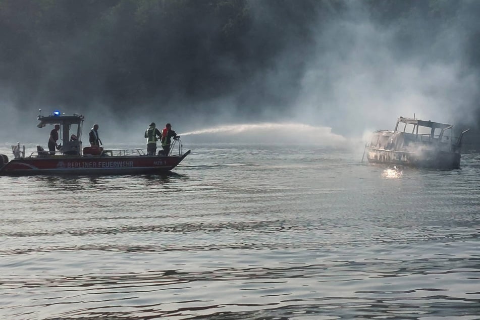 Die Feuerwehr löscht den brennenden Kahn von einem Mehrzweckboot aus, bevor er zu einer Rettungsstation geschleppt wurde.