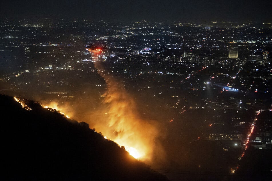 Auch in den Hollywood Hills sind die Flammen angekommen, ein Hubschrauber wirft Wasser auf das sogenannte Sunset Fire.