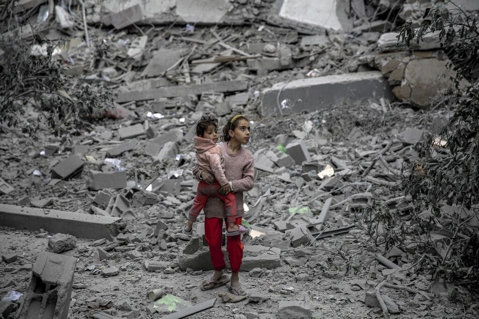 A Palestinian girl carries a child through the rubble of houses destroyed by Israeli bombardment in Gaza City.