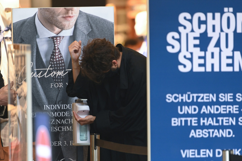 Kunden desinfizieren ihre Hände am Eingang eines Textilgeschäfts. (Archivbild)
