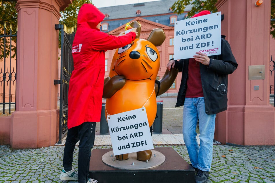 Mit einem Banner mit der Aufschrift "Keine Kürzungen bei ARD und ZDF!" machte die Maus am Mittwoch auch vor dem rheinland-pfälzischen Landtag Halt.