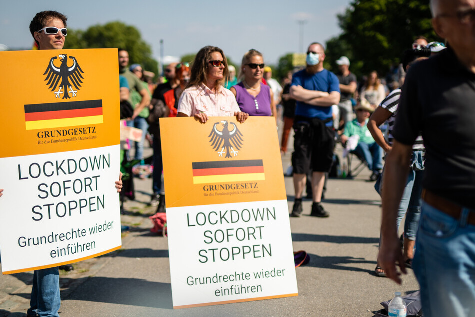 Teilnehmer tragen auf dem Cannstatter Wasen bei der Protestkundgebung der Initiative "Querdenken" Schilder mit der Aufschrift "Lockdown sofort stoppen". (Archivbild)