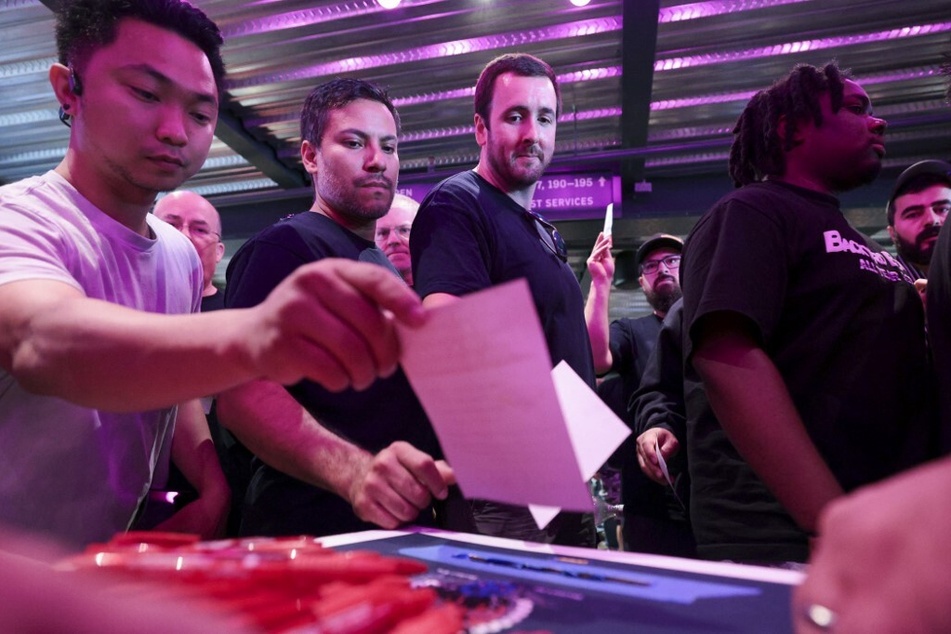 International Association of Machinists and Aerospace Worker Union District 751 members drop their ballots into a ballot box during an early strike-sanction vote event.