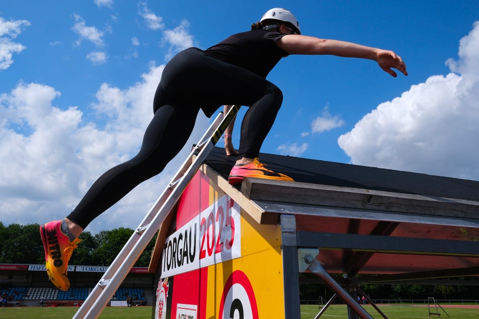 Eine Feuerwehrsportlerin trainiert im Hafenstadion das Überwinden eines Hindernisses mittels Leiter.