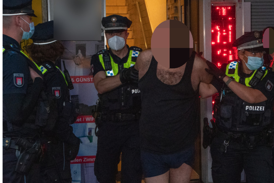 Die Polizei führt einen Mann in Boxershorts und Unterhemd ab.