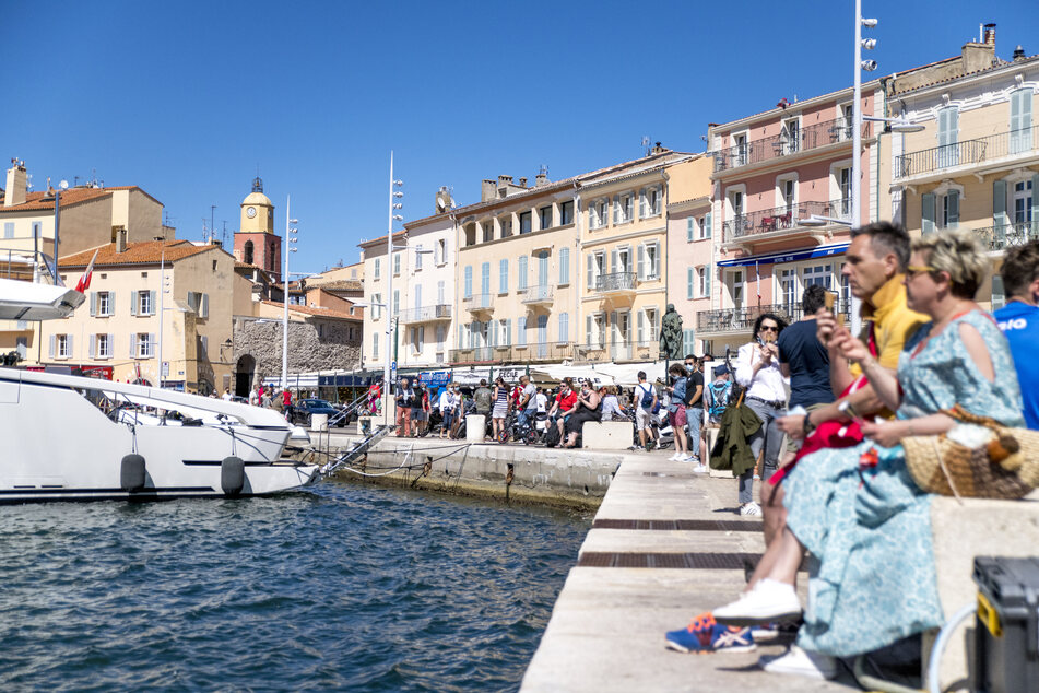 Frankreich, Saint-Tropez: Zahlreiche Menschen sitzen am Hafen "Port de Saint Tropez" und schauen aufs Meer.