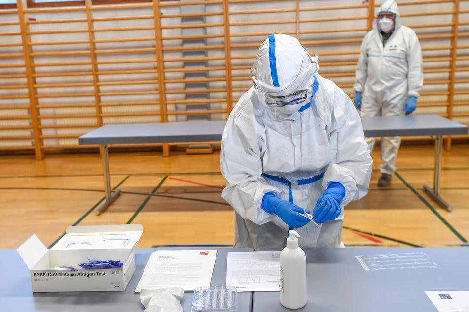 Ein Mitarbeiter steht mit einem Test und Unterlagen in einer Teststation.