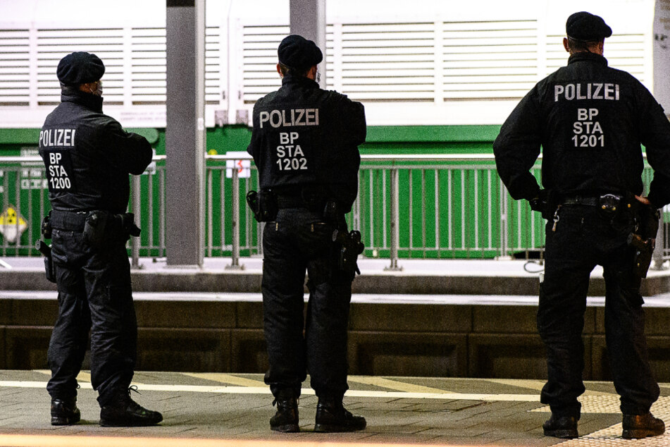 Einsatzkräfte der Bundespolizei stehen auf einem Bahnsteig vor einem von insgesamt sechs Castor-Behältern im Bahnhof von Hünfeld.
