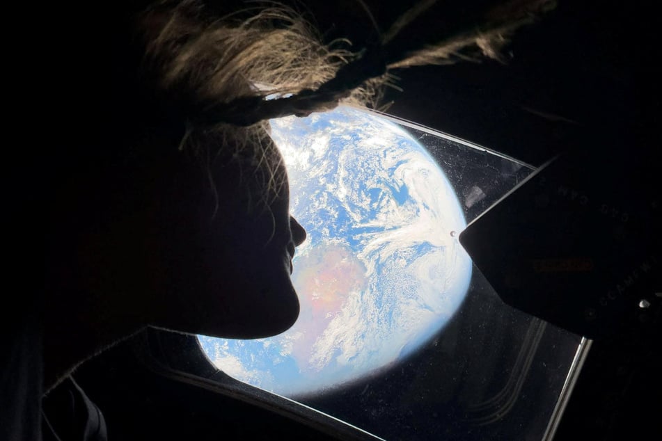 NASA astronaut and Artemis II mission specialist Christina Koch peers out of one of the Orion spacecraft's main cabin windows, looking back at Earth, on April 2, 2024.