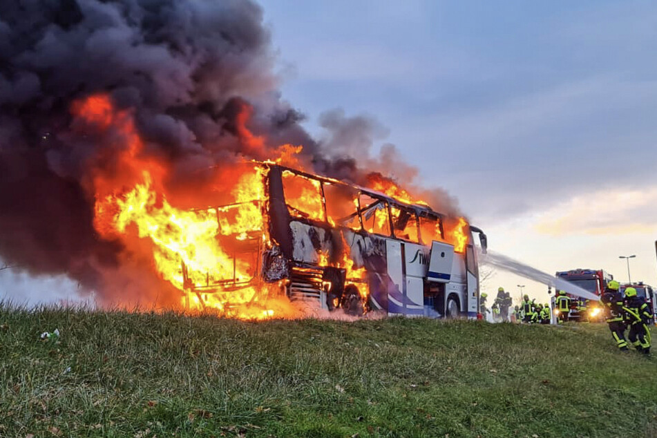 Feuerwehrleute kämpfen gegen die meterhohen Flammen am Bus.
