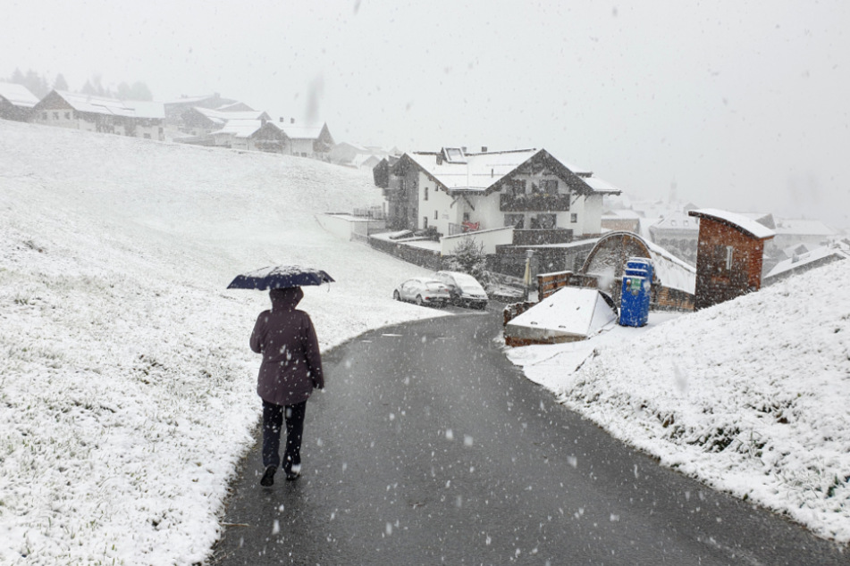 Österreich, Fiss: Eine Spaziergängerin geht bei Schnee an einer Straße entlang.