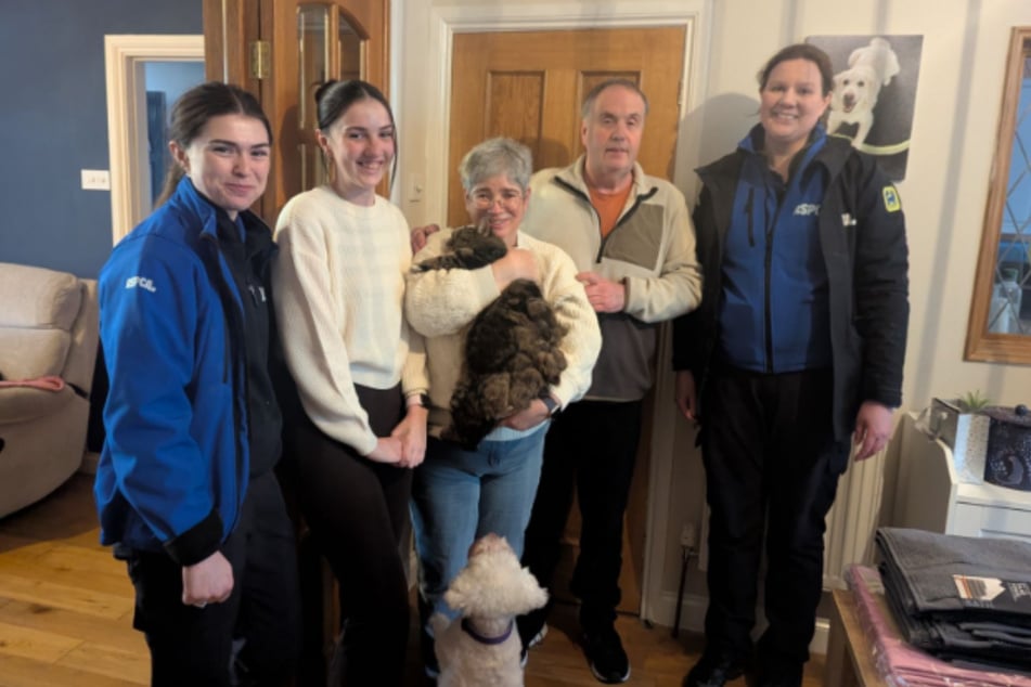 Mandy Davis hält Alfie überglücklich in ihren Händen, während ihre Familie und zwei der Retterinnen in die Kamera lächeln.