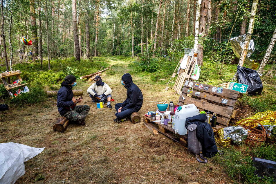 In ihrem Waldlager basteln die Besetzer an Transparenten - oder singen Lieder zur Ukulele.
