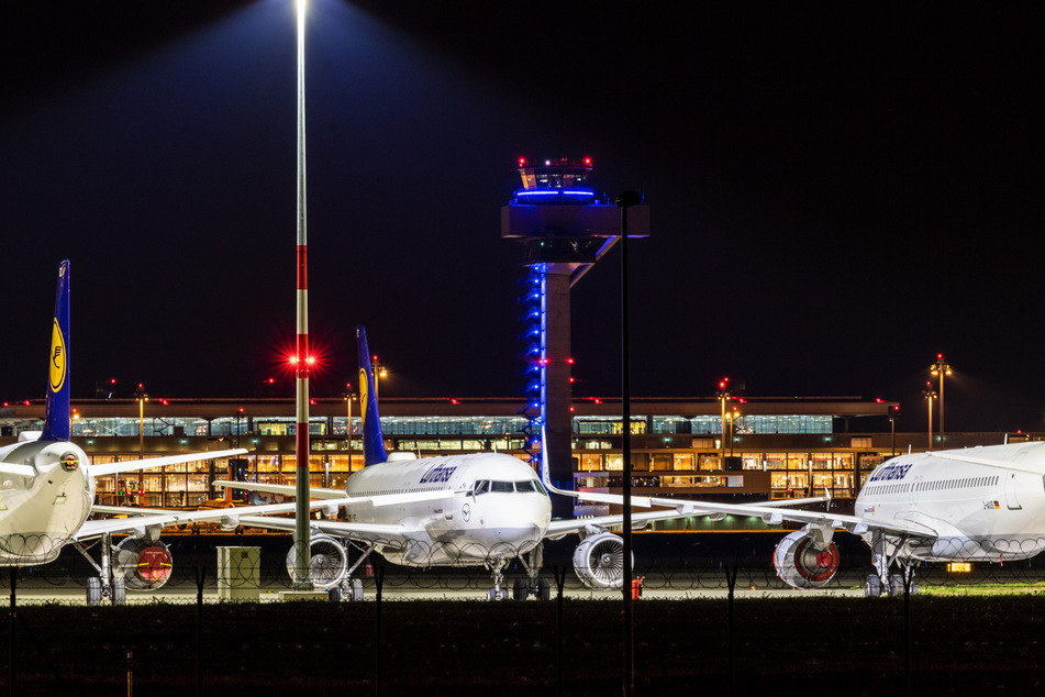 Flugzeuge der Lufthansa stehen hinter dem Terminal 1 des Hauptstadtflughafens Willy Brandt hinter einem Zaun.