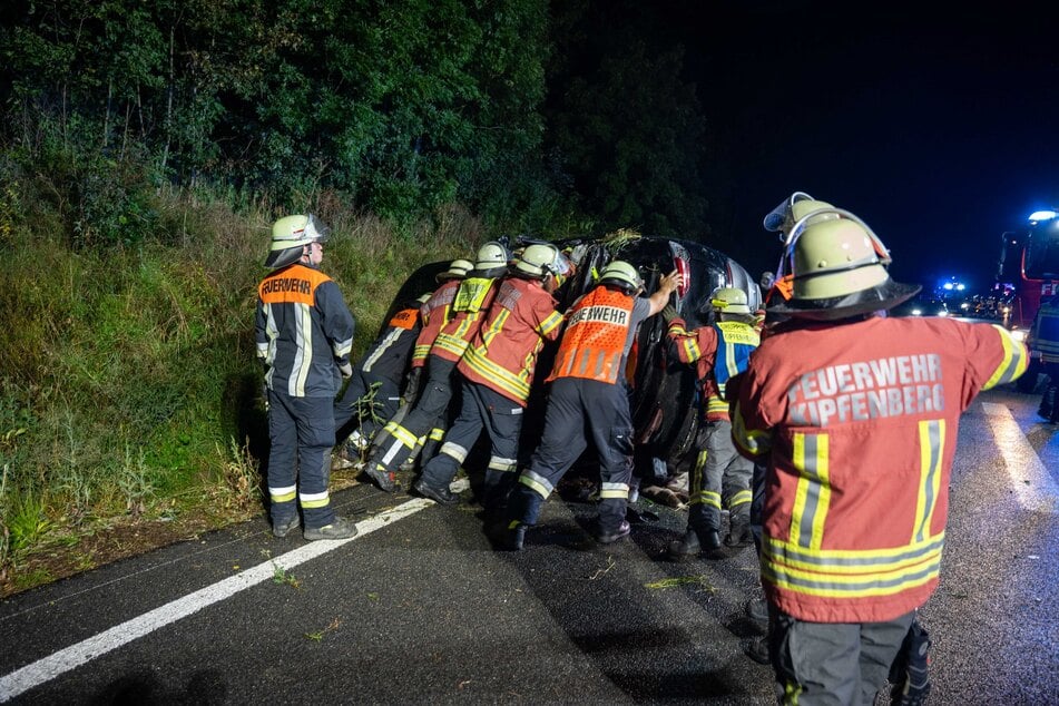 Feuerwehrleute stellen den Opel mit vereinten Kräften wieder auf seine Räder.