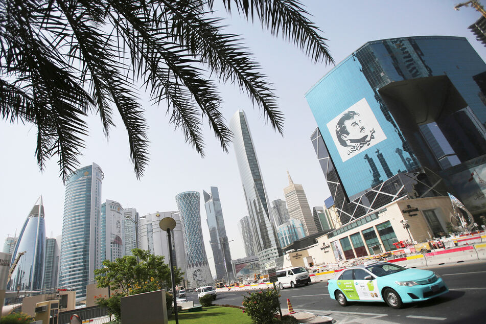 Ein Taxi fährt an einem Gebäude mit einem Bild des Emirs von Katar, Sheikh Tamim bin Hamad Al Thani, vorbei.
