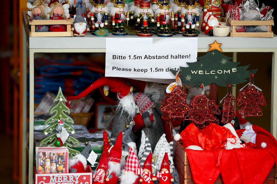 In einem Geschäft hängt ein Schild mit der Aufschrift "Bitte 1,5m Abstand halten!" zwischen Weihnachtsdekoration.