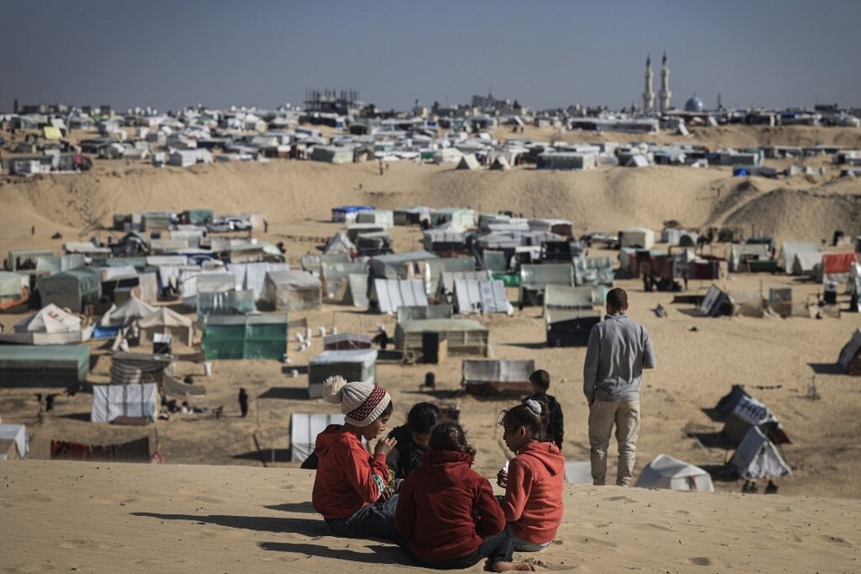 Displaced Palestinian children play on a sand dune overlooking a makeshift camp on the Egyptian border, west of Rafah in the southern Gaza Strip, on January 14, 2024.