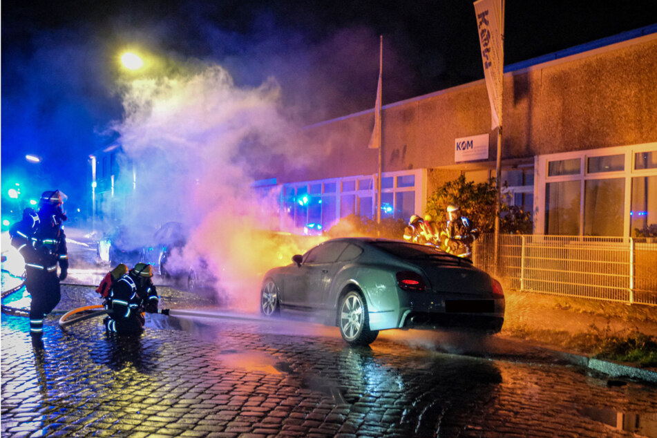 Feuerwehrleute löschen ein in Brand geratenes Auto.