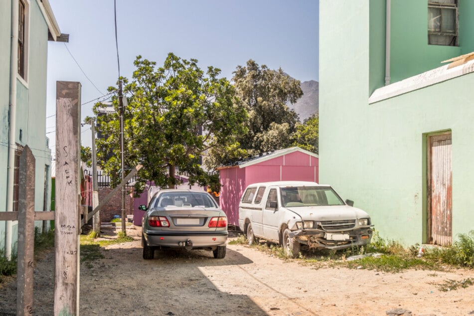 Südafrika: Zwei alte und zum Teil schrottreife Gebrauchtwagen stehen in einem Stadtviertel von Kapstadt.