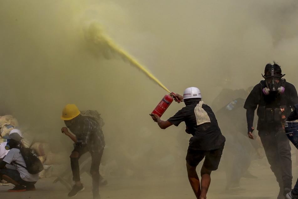 Demonstranten in Yangon benutzen einen Feuerlöscher zum Schutz vor Einsatzkräften. Auch am Mittwoch gingen landesweit Tausende gegen die Generäle auf die Straße.