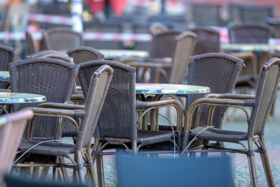 Leere Stühle und Tische stehen in einem geschlossenen Straßencafe. 