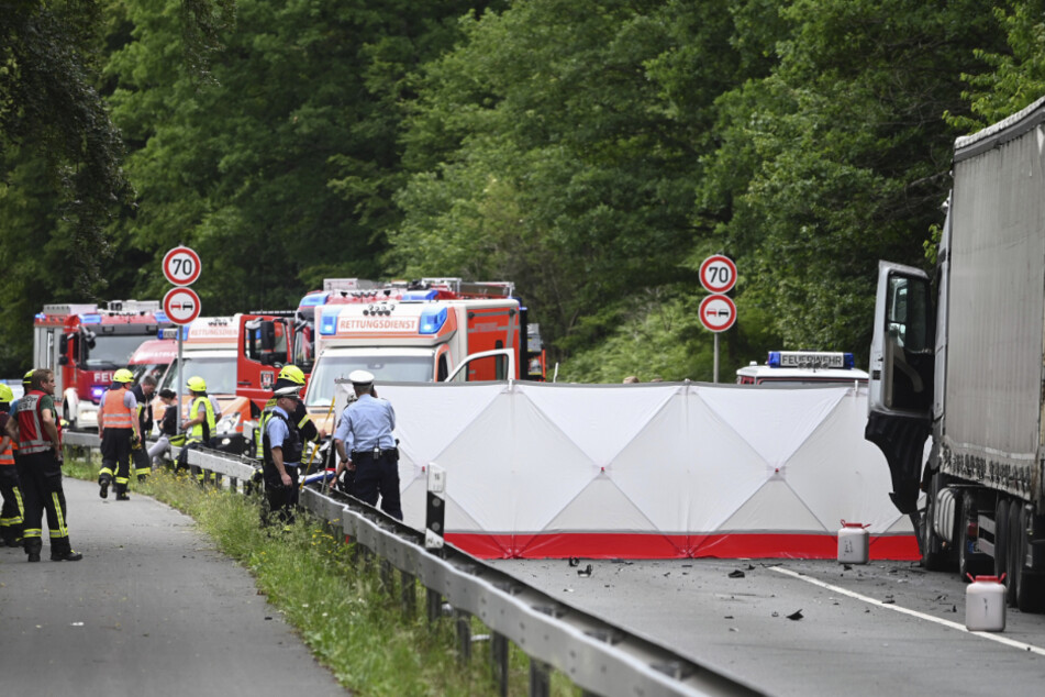 Feuerwehrleute arbeiten an einer Unfallstelle hinter einer Sichtschutzwand.