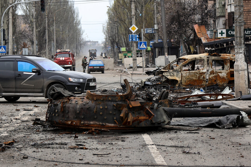 Ein zerstörter Panzer und ein zerstörtes Fahrzeug sind als Gefechtsüberreste auf einer Straße zu sehen.