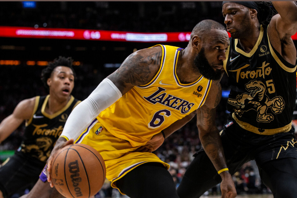 Los Angeles Lakers' LeBron James (c.) drives at Toronto Raptors Precious Achiuwa (r.) during the second half of basketball action in Toronto on Friday.