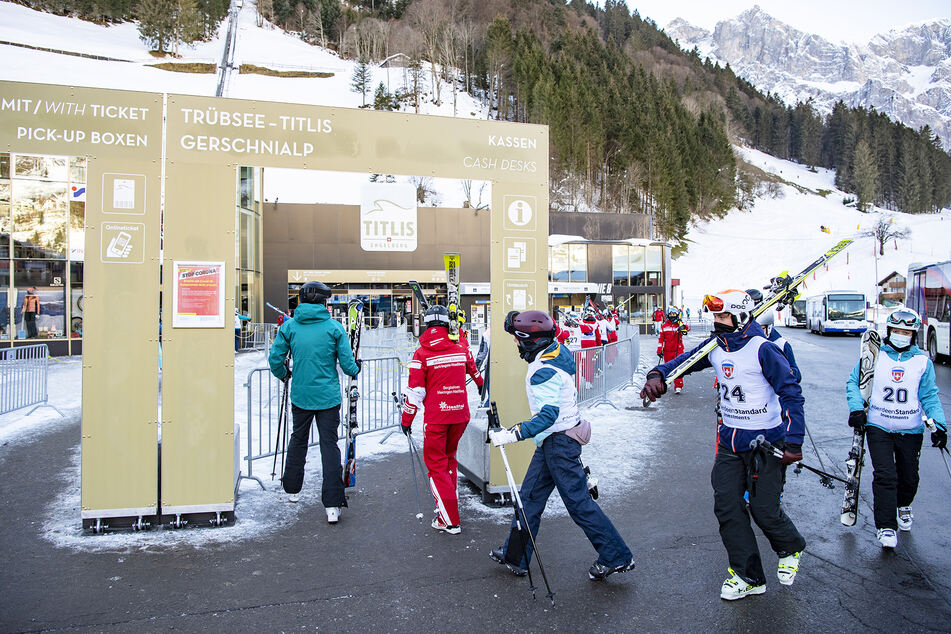Skifahrer gehen vor der Talstation der Engelberg-Titlis-Bergbahnen durch einen Sicherheitsbereich.