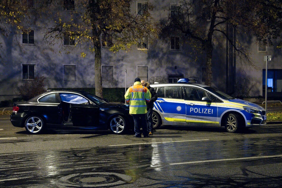 Polizisten untersuchen nach einem Unfall in München ein beschädigtes Auto.