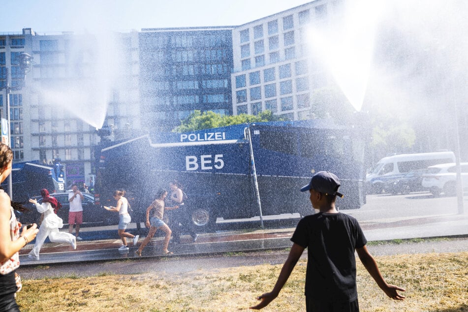 Die Berliner Polizei setzt in Mitte für etwas Abkühlung auf einen Wasserwerfer.