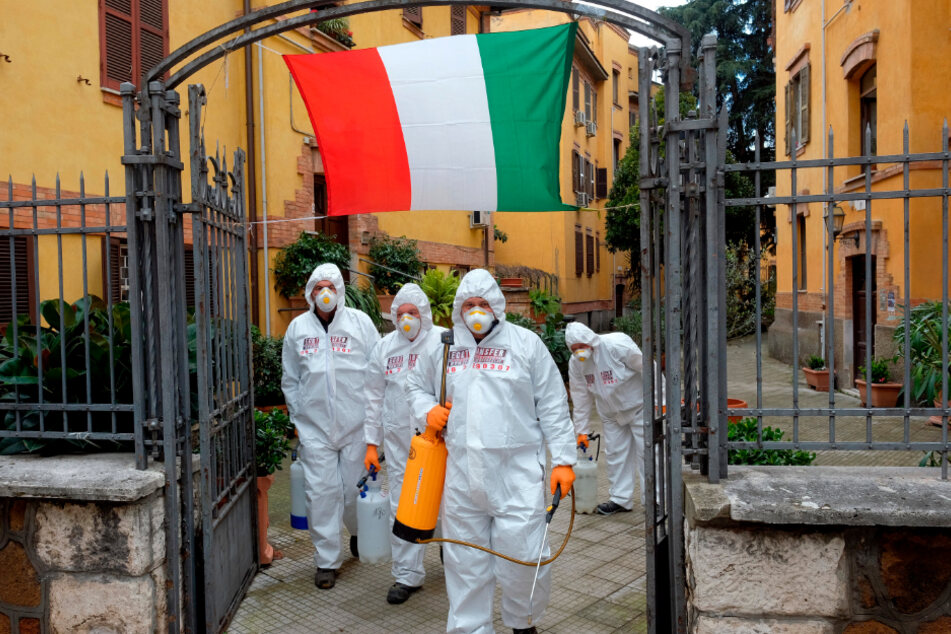 Rom: Arbeiter in Schutzkleidung desinfizieren die Gehwege in einem Viertel, um die Ausbreitung des Coronavirus einzudämmen.