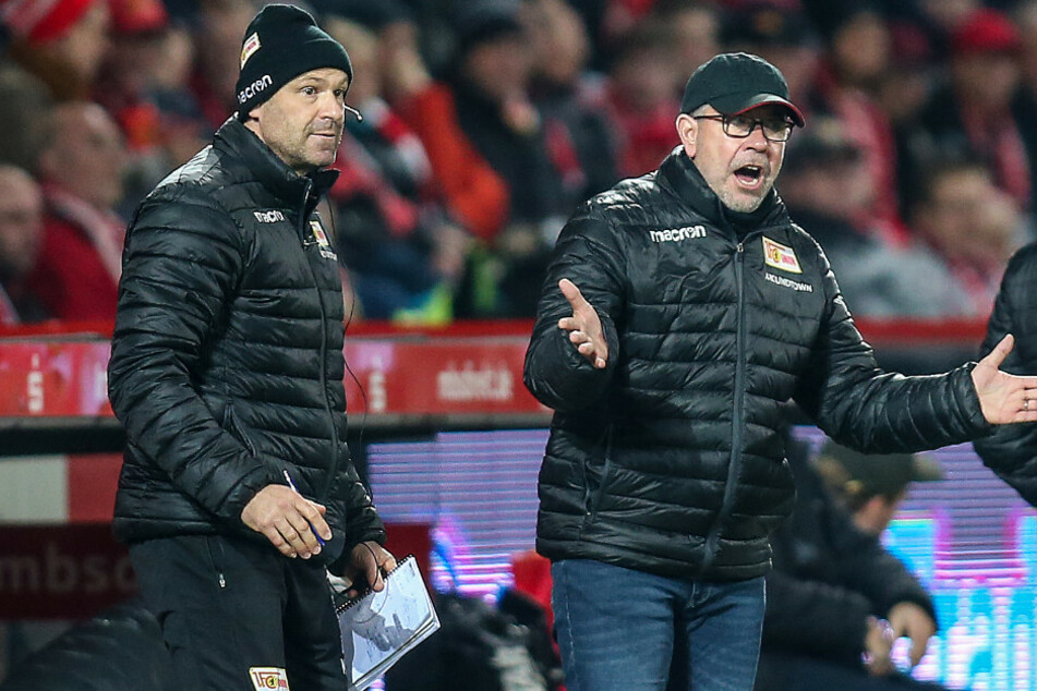 Berlins Trainer Urs Fischer (M) steht gestikulierend am Spielfeldrand neben Co-Trainer Markus Hoffmann (l).