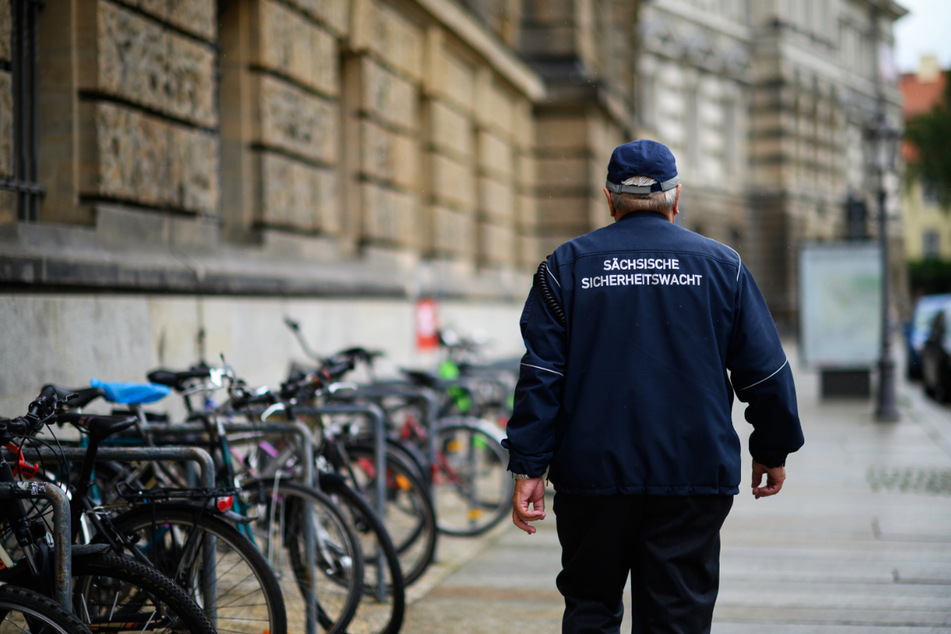 Ein ehrenamtlicher Mitarbeiter der Sächsischen Sicherheitswacht läuft einen Fußweg in der Innenstadt entlang.