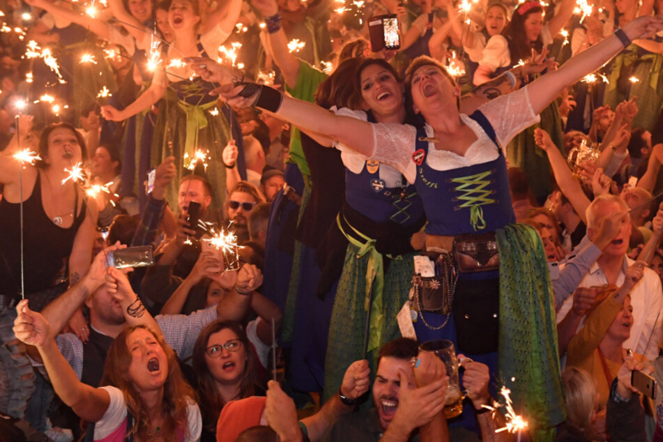 Bedienungen stehen im Hofbräu-Zelt beim traditionellen Kehraus auf den Tischen und feiern.