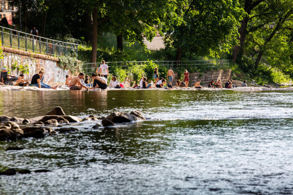 Freiburg: Menschen sitzen an den Ufern der Dreisam und genießen das schöne Wetter.