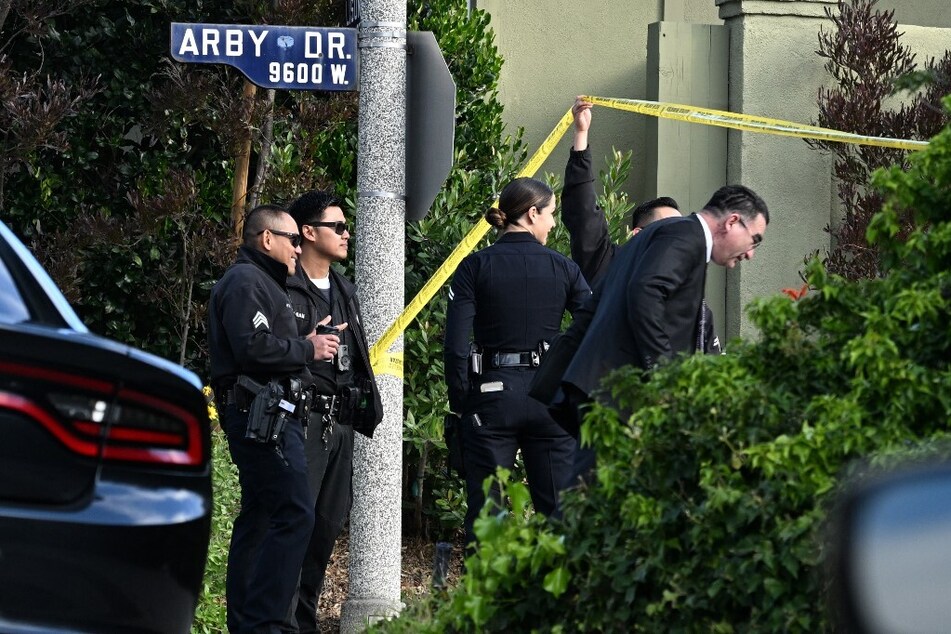 Law enforcement officers lift police tape for an investigator after an early morning shooting in the Beverly Crest neighborhood.