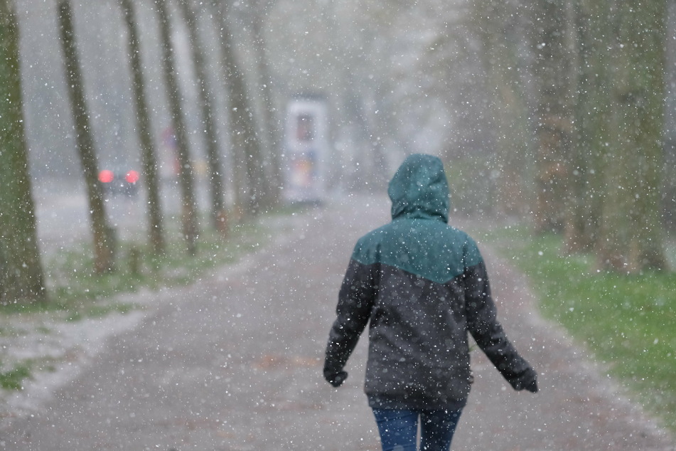 Während eines Graupelschauers geht eine Frau durch den Clara-Zetkin-Park. Mieses Wetter stand in den letzten Monaten in Sachsen auf der Tagesordnung.