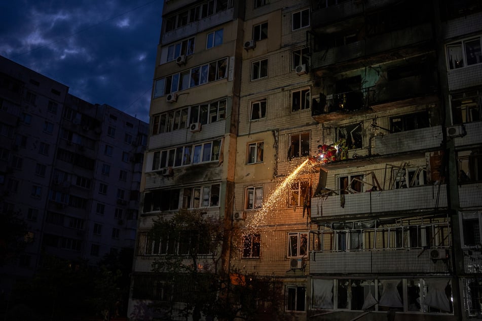 Feuerwehrleute räumen in Kiew Trümmer von einem Balkon eines Wohnhauses, das durch einen russischen Angriff beschädigt wurde.