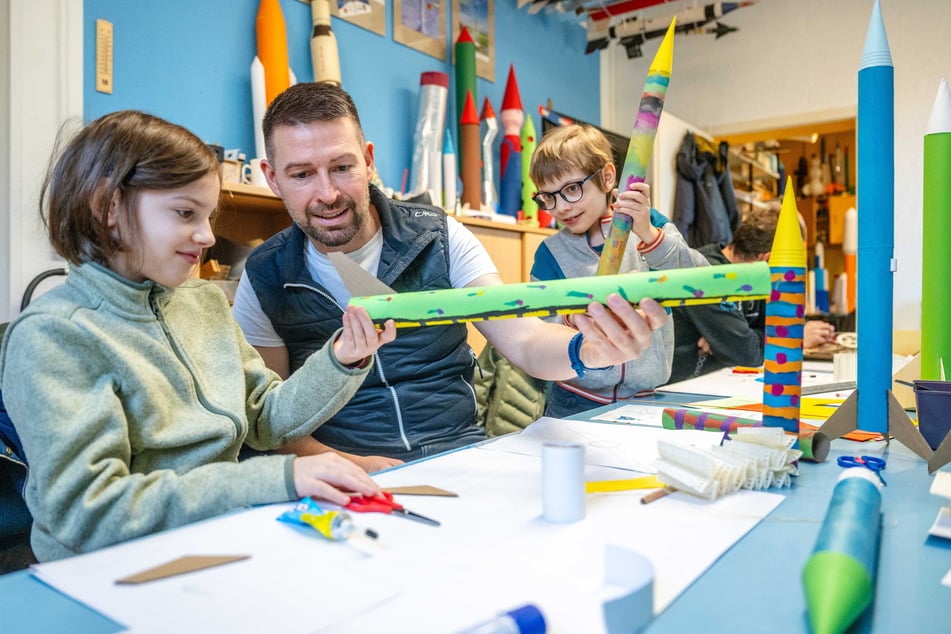 Alma (10, l.) bastelt an ihrem Flugkörper mit Jonas Büchel (43, M.). Almas Bruder Johann (8) hat bereits eine Spitze auf seiner Rakete.