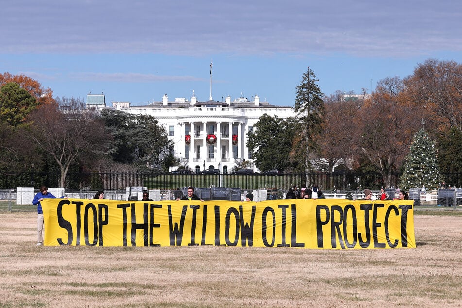 Activists unfurl a banner demanding President Biden stop the Willow Project on the Ellipse outside the White House on December 2, 2022.