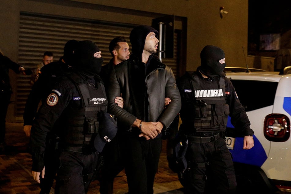 Andrew Tate is escorted by police officers outside the headquarters of the Directorate for Investigating Organized Crime and Terrorism in Bucharest (DIICOT) after being detained.