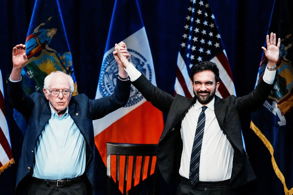 Senator Bernie Sanders (l.) and New York City mayoral candidate Zohran Mamdani gesture to the crowd at the end of a town hall on affordability at the Leonard & Claire Center for the Performing Arts in Brooklyn on September 6, 2025.