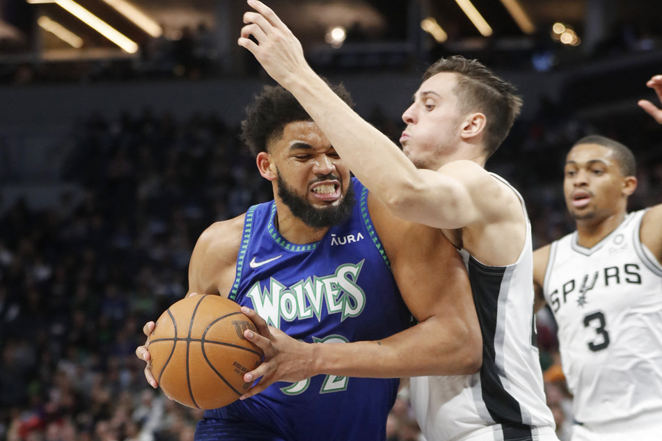 Karl-Anthony Towns (l.) goes up against Zach Collins (c.) in the T'Wolves win over the Spurs.