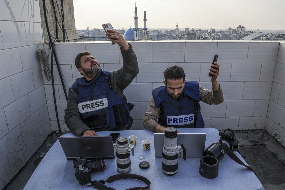 Palestinian journalists attempt to connect to the internet using their phones in Rafah in the southern Gaza Strip.