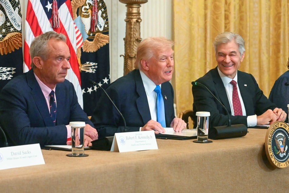 Dr. Mehmet Oz (r.) is facing ridicule after he recently revealed he keeps a giant painting of President Donald Trump (c.) hanging in his office.