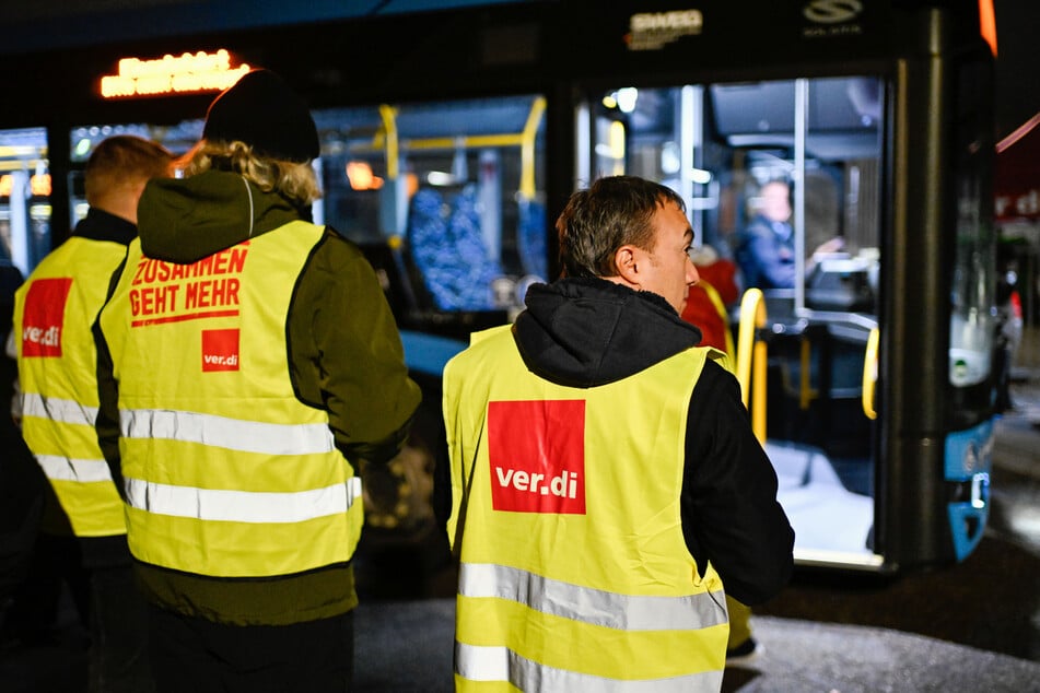 Streikende stehen bei einem Warnstreik der Gewerkschaft ver.di am Gelände der SWEG (Südwestdeutsche Landesverkehrs-GmbH) vor einem Bus.